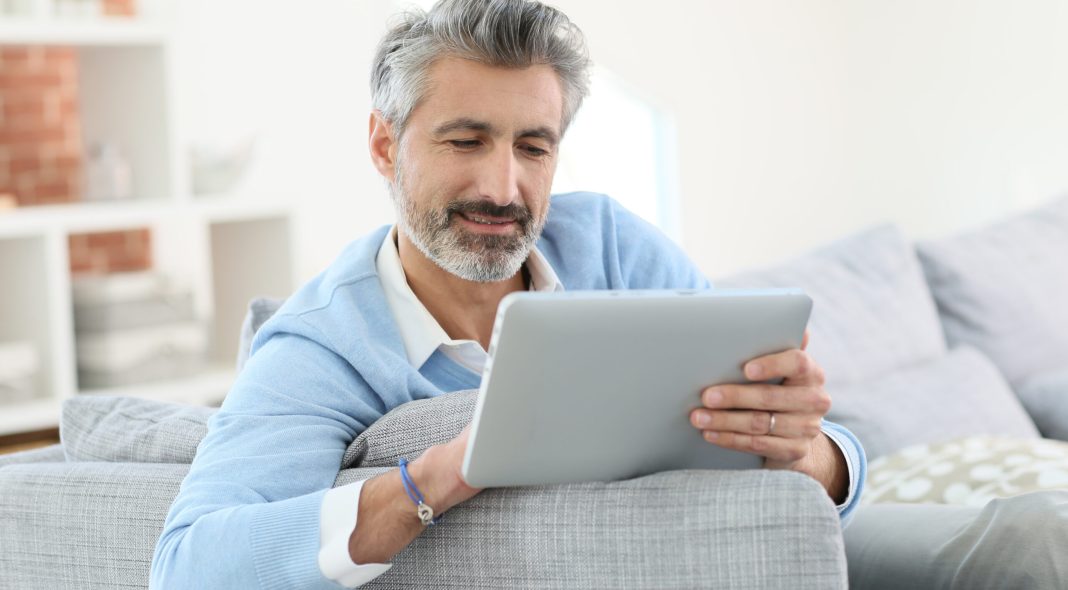 Mature man sending email with digital tablet